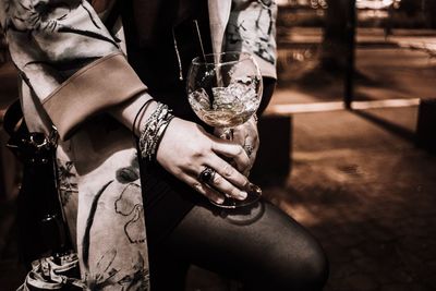 Midsection of woman holding wineglass