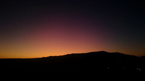 Scenic view of silhouette mountains against orange sky