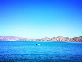 Boats in sea against blue sky