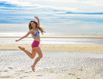 Full length of young woman at beach against sky