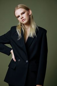 Portrait of young woman standing against yellow background