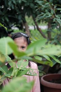 Portrait of girl standing by plant on field