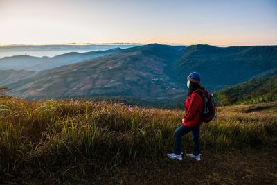 Rear view of woman looking at mountains against sky