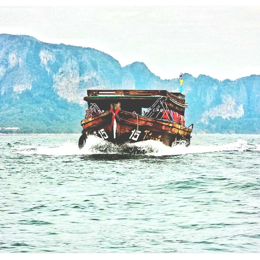 BOAT IN SEA AGAINST MOUNTAIN