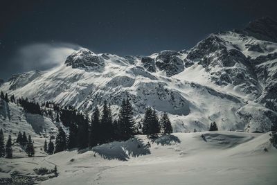 Scenic view of snowcapped mountains against sky at night