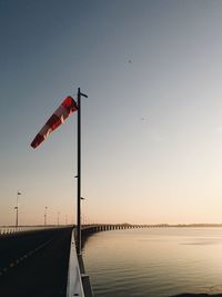 Flag on street light against sky during sunset