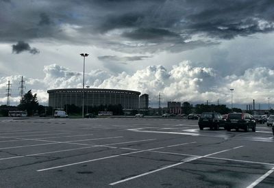 Road passing through city against cloudy sky