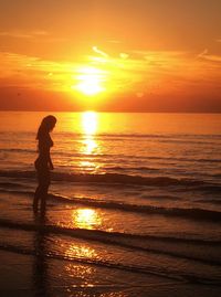 Silhouette man standing at beach during sunset