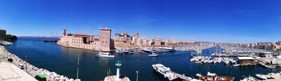 High angle view of boats in city against blue sky