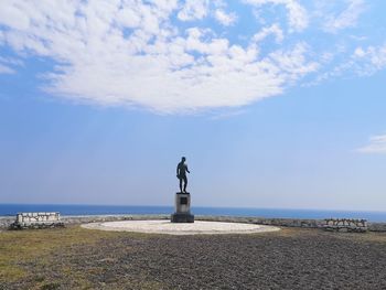 Rear view of man standing on beach against sky