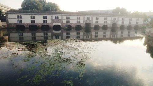 Reflection of buildings on river against sky