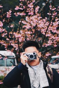 Young man with camera standing at park during winter