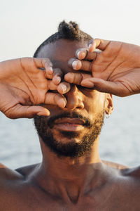 Shirtless man covering eyes with hands