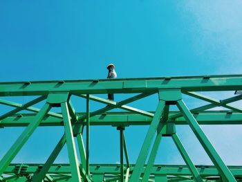 Low angle view of woman standing against clear blue sky