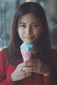 Close-up portrait of smiling young woman eating ice cream