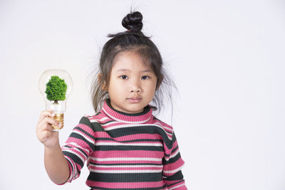 Portrait of cute girl standing against white background