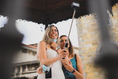 Young woman holding camera while standing outdoors