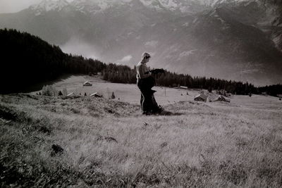 Side view of woman standing on field against sky