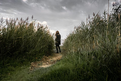 Rear view of woman walking on field against sky