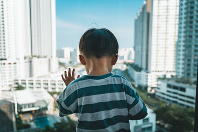 Full length of boy standing by buildings in city