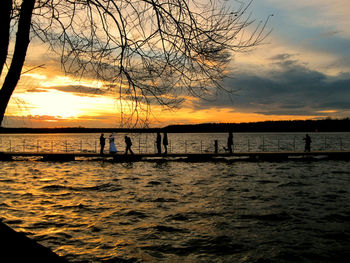 Silhouette trees by sea against sky during sunset