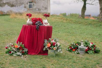 Festive wedding table setting outdoors in red, floristry, bouquets in vases