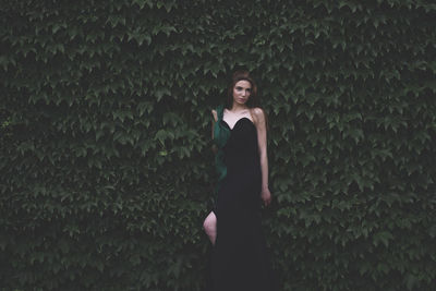 Beautiful young woman posing while looking away against plants