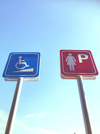 Low angle view of road sign against clear blue sky