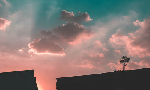 Low angle view of silhouette building against dramatic sky