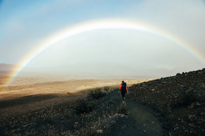 Female backpacker hiking with double rainbow in haleakala crater in maui, hawaii.