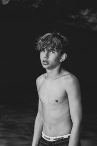 Portrait of shirtless boy standing against water