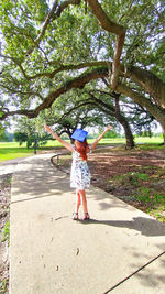 Full length of girl standing by tree