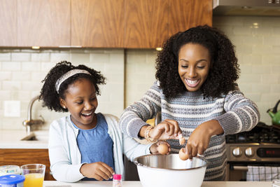 Happy mother and daughter making cupcakes in kitchen