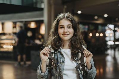 Portrait of smiling girl with long hair standing at station