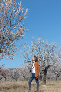 Low angle view of woman standing on field against clear blue sky