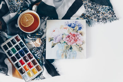 Directly above shot of tea and paintings against white background