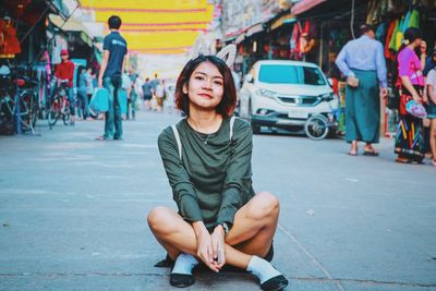 Full length of a smiling young woman sitting on street