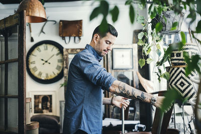 Side view of mid adult man lifting chair in interior design shop