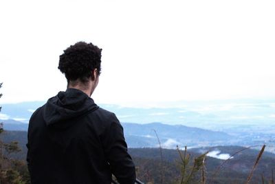 Rear view of man standing on mountain against sky