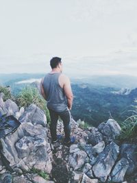 Rear view of man looking at mountains against sky