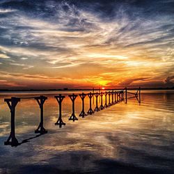 Pier on sea against cloudy sky