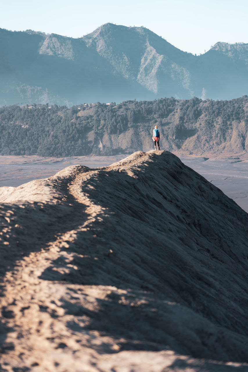 Man standing on mountain at arid landscape