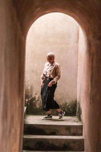 Full length of woman standing against wall