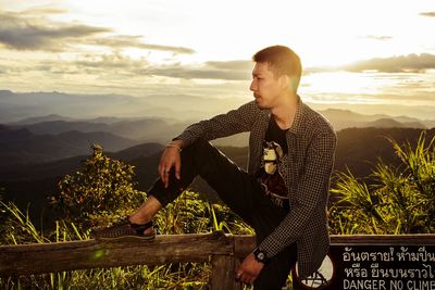 Young man standing on mountain against sky