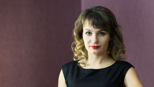 Portrait of beautiful young woman against wall