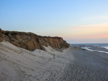 Scenic view of beach against clear sky during sunset