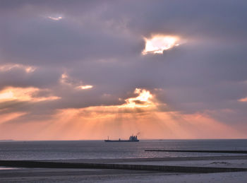 Scenic view of sea against cloudy sky at sunset