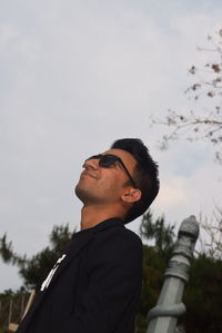 Young man looking up against sky