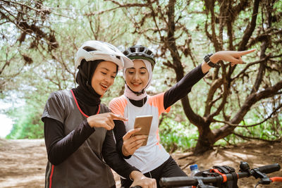 Female friends gesturing while holding mobile phone