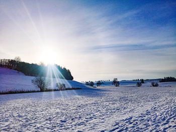 Scenic view of snow covered bright sun against sky